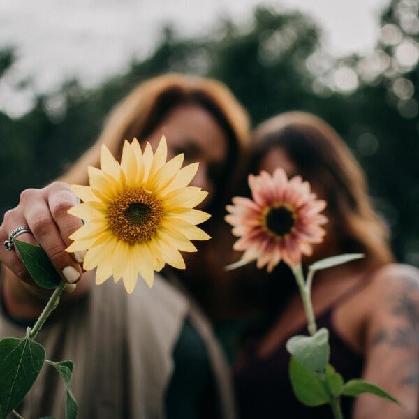 Zwei Frauen halten Sonnenblumen in die Kamera